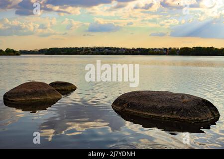 Große Steine im See, Wolken spiegeln sich im Wasser, bei Sonnenuntergang Stockfoto