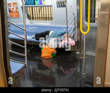 Eine obdachlose Frau schläft am Samstag, den 30. April 2022, in einem U-Bahn-Zug der E-Linie in New York. (© Richard B. Levine) Stockfoto