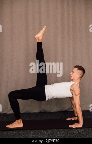 Ein gutaussehender Athlet führt ein Workout durch und hebt sein Bein nach oben Stockfoto