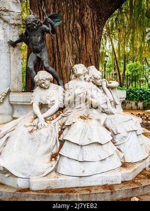 Skulpturale Gruppe von Lorenzo Coullaut Valera im Gustavo Adolfo Bécquer Turnaround. Drei weibliche Figuren, die auf einer Bank sitzen und die drei Zustände der Liebe symbolisieren: "Aufgeregte Liebe", "besessene Liebe" und "verlorene Liebe", und die Bronzestatue des Amors, die "die Liebe, die schmerzt - Maria Luisa Park - Sevilla, Spanien Stockfoto