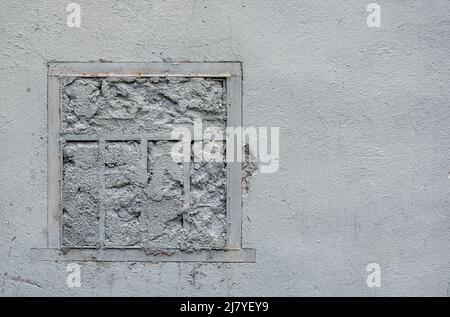 Gemauerte Fenster mit einem Gitter, in einer alten, weiß gestrichenen Wand. Illustratives Foto oder Textur Stockfoto