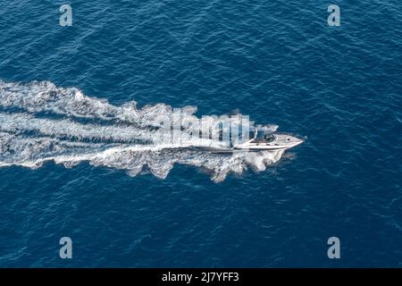 Das Boot schwimmt mit hoher Geschwindigkeit auf der blauen Weite des Meerwassers, Draufsicht Stockfoto