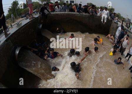 Lahore, Pakistan. 08.. Mai 2022. Die pakistanischen Menschen kühlen sich während des heißen Wetters in Lahore, Pakistan, am 8. Mai 2022 in einem Kanal ab. Im März und April erlebten Gebiete in Indien und im benachbarten Pakistan extreme Hitze, die über eine Milliarde Menschen Temperaturen weit über 40 Grad Celsius (104 Fahrenheit) aussetzte. Die wärmsten Monate des Jahres stehen noch bevor. (Foto von Rana Sajid Hussain/Pacific Press/Sipa USA) Quelle: SIPA USA/Alamy Live News Stockfoto