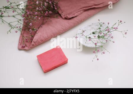 Handgemachte Naturseife auf weißem floralem Hintergrund. Seifenherstellung. Seifenleisten. Spa, Hautpflege. Natürliche Bio-Spa-Kosmetikprodukte auf weißem Tisch von Stockfoto