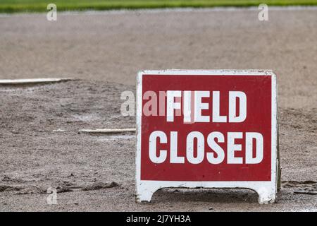 Rot-weißes Schilderlesefeld auf schlammigem Baseballfeld geschlossen. Stockfoto