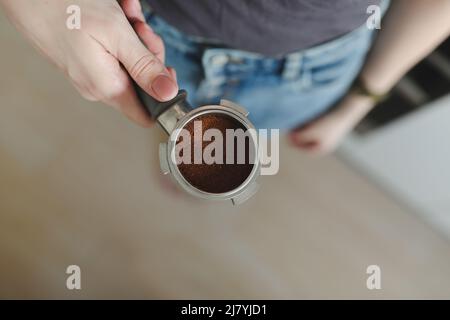 Der Barista bereitet Kaffee zu und hält Portafilter in der Hand von einer Kaffeemaschine. Nahaufnahme Stockfoto