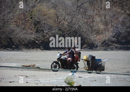 Männer schieben das Boot in die Brandung am Strand von Costa Rica Stockfoto