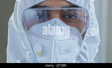 Porträt des männlichen Arztes Krankenschwester Wissenschaftler Arzt trägt spezielle schützende chemische weiße Anzug einheitliche Brille und Atemschutzmaske Blick auf die Kamera Stockfoto