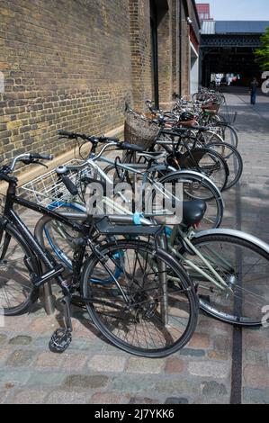 Eine Reihe von verschiedenen Fahrrädern, die an einem Fahrradständer vor der Central Saint Martins Kunstschule in Coal Drops Yard geparkt wurden. London, England, Großbritannien. Stockfoto