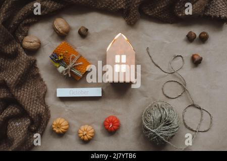 Gemütliches Herbstgemisch mit Papierhaus, umgeben von Herbstblättern, Kerzen und einem Blick auf den Kürbis. Einrichtung im Stil einer Hygge-Wohnung. Halloween und Thanksgiving Stockfoto