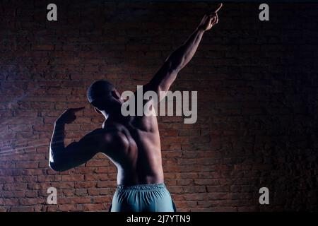 Junger muskulöser afroamerikanischer Mann, der Liegestütze macht und wegschaut Stockfoto