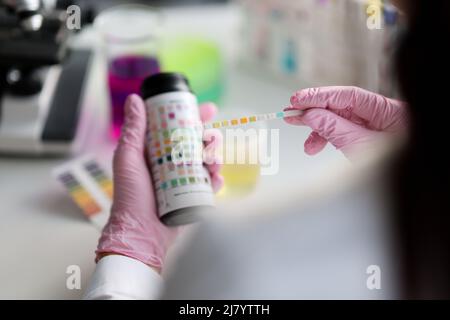 Clever Wissenschaftler halten Lackmus-Testpapier für die Bodenanalyse, Papiere zeigen Säure Stockfoto