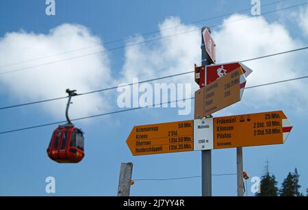 Schilder für verschiedene Bergwanderwege in der Schweiz mit Gondel im Hintergrund Stockfoto