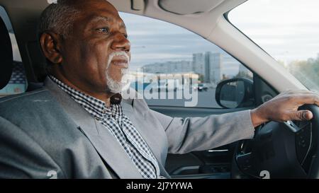 Alter afroamerikanischer Mann, der Auto fährt ernst nachdenklich älterer Mann verlässt Parkplatz reifer Geschäftsmann, der genau auf Straße fährt, nähert sich Stockfoto