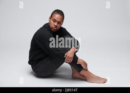 Niedergeschlagen junge schwarze Frau mit Angst auf dem Boden sitzen und umarmen Knie, schwarz lebt Materie Konzept Stockfoto