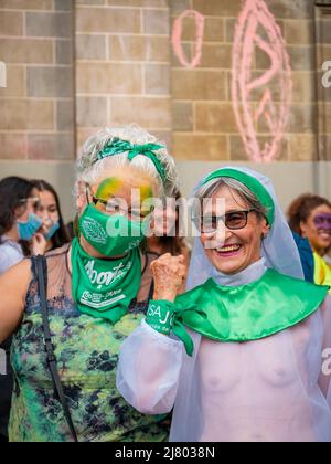 Medellin, Antioquia, Kolumbien - 8 2022. März: Zwei ältere Frauen in grüner Kleidung posiert vor dem Frauenmarsch zum Frauentag für ein Foto Stockfoto