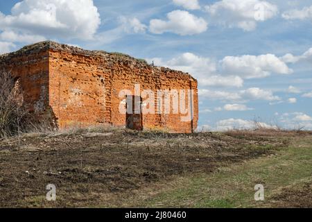 Eine ruinierte alte christliche Kirche aus rotem Backstein im Sommer am Tag gegen einen blauen Himmel. Stockfoto