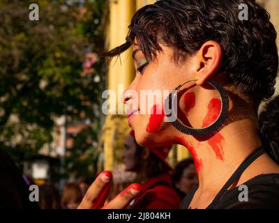 Medellin, Antioquia, Kolumbien - 8 2022. März: Junge Frau mit roter Farbe auf ihrem Gesicht am Frauentag Stockfoto