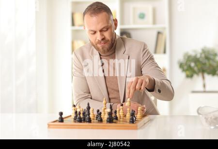 Junger Mann, der alleine zu Hause Schach spielt Stockfoto