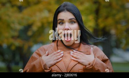 Porträt erstaunt hispanisch glückliches Mädchen erhält unerwartete Überraschung im Park im Freien junge enthusiastische Frau öffnet den Mund von dem, was sah Frau fühlt Stockfoto