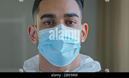 Porträt traurig männlich Gesicht müde ethnisch arabisch hispanic Arzt Mann Arzt Chirurg Spezialist tragen Schutzmaske während Pandemie Corona in Stockfoto