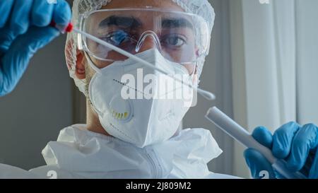 Porträt arabisch hispanic Mann Arzt Arzt Arzt in PSA-Schutzanzug durchgeführt Staus Tupfer von nicht erkennbaren Person, um auf Coronavirus zu testen Stockfoto