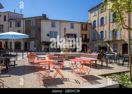 SAUVE, FRANKREICH - 5.. APRIL 2022: Typischer Platz mit Springbrunnen und Cafétischen in Sauve an einem sonnigen Frühlingsnachmittag in Gard, Südfrankreich Stockfoto