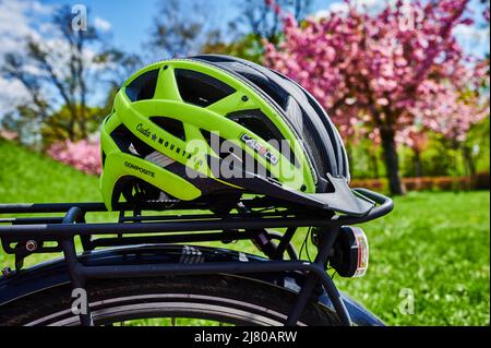 Berlin, Deutschland - 27. April 2022: Gelber Fahrradhelm auf dem Gepäckträger eines Fahrrads. Stockfoto