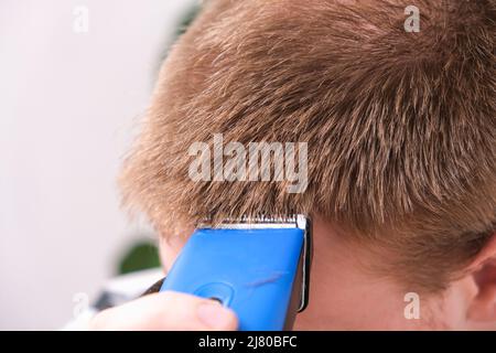 Ein Mann schneidet sich mit einem Haarschneider die Haare. Schneiden einer kurzen Frisur zu Hause. Nahaufnahme. Stockfoto