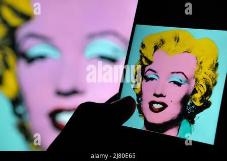 Geschossen Sage Blue Marilyn Kunstwerk auf einem Bildschirm von ipad umgeben von Dollar-Banknoten. Ein Porträt von Marilyn Monroe von Andy Warhol. Stafford, Großbritannien Stockfoto