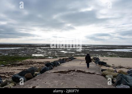 Rückansicht einer Frau, die am Strand steht und im Winter auf die Ile de Re, Rivedoux et Ars en Re, Charente Maritime, Frankreich blickt Stockfoto