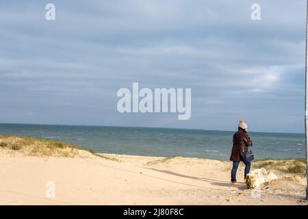 Rückansicht einer Frau, die im Winter am Strand mit Blick auf das Meer steht, Ile de Re, Rivedoux et Ars en Re, Charente Maritime, Frankreich Stockfoto