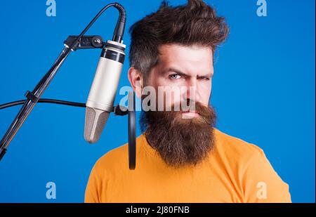 Bärtiger Mann singt im Kondensatormikrofon. Professioneller Sänger. Singen im Studio. Karaoke. Stockfoto