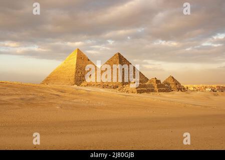 Giza Pyramid Complex bei Sonnenuntergang mit Stadtbild im Hintergrund, Kairo, Ägypten Stockfoto