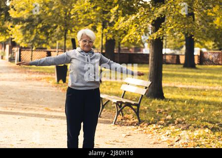 Ältere Rentnerin Europäische grauhaarige Dame kümmert sich um ihre Gesundheit, indem sie im Freien Sport macht. Vitalität und Kraft unter Senioren. Hochwertige Fotos Stockfoto