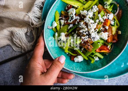 Ansicht von oben einer Frau, die eine Schüssel mit griechischem Salat in der Hand hält Stockfoto