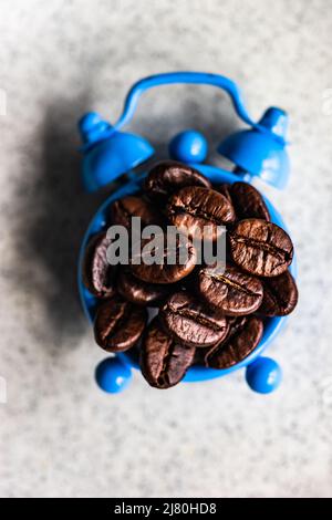 Geröstete Kaffeebohnen auf einem Vintage-Wecker als Weckruf am Morgen Stockfoto