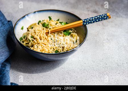 Schüssel mit asiatischer Nudelsuppe mit Koriander, Tomaten, Karotten und Chili Stockfoto