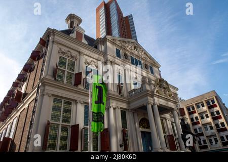 Historisches weißes Gebäude mit roten Fensterläden und klassischer Architektur in einer urbanen Umgebung unter blauem Himmel Stockfoto