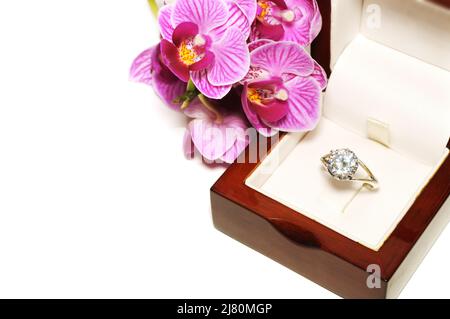Dimond Verlobungsring in einer Holzkiste und Orchidee. Romantisches Image und liebevolle Proposition Stockfoto