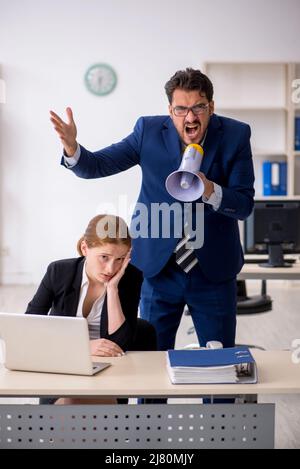 Wütender männlicher Chef und junge weibliche Angestellte am Arbeitsplatz Stockfoto