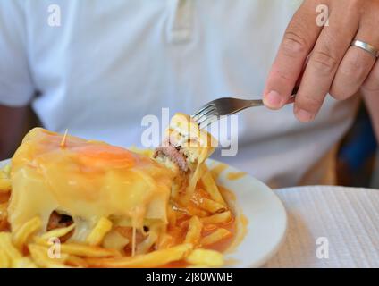 Eine portugiesische sandwich Francesinha mit Pommes frites originelles Gericht in Porto, Portugal serviert. Stockfoto