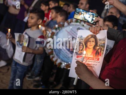 Gaza, Palästina. 11.. Mai 2022. Eine brennende Kerze und ein Foto des Journalisten Shireen Abu Aqleh während einer Kerzenlichtmahnwache in der Nähe der Ruinen des Al-Jazeera-Kanalgebäudes in Gaza-Stadt, um ihre Tötung zu verurteilen. Shireen Abu Aqleh, ein Al-Jazeera-Korrespondent, wurde getötet, als er über eine Invasion im Flüchtlingslager Dschenin im Westjordanland berichtete. Kredit: SOPA Images Limited/Alamy Live Nachrichten Stockfoto