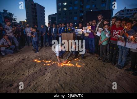 Gaza, Palästina. 11.. Mai 2022. In einer Kerzenlichtmahnwache zünden Palästinenser Kerzen an, um die Tötung des Journalisten Shireen Abu Aqleh in der Nähe der Ruinen des Al-Jazeera-Kanalgebäudes in Gaza-Stadt anzuprangern. Shireen Abu Aqleh, ein Al-Jazeera-Korrespondent, wurde getötet, als er über eine Invasion im Flüchtlingslager Dschenin im Westjordanland berichtete. Kredit: SOPA Images Limited/Alamy Live Nachrichten Stockfoto