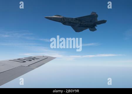Ein F-22 Raptor der US Air Force mit dem 192. Fighter Wing fliegt mit dem 117. Air Betanking Wing an der Seite eines KC-135 Stratotankers, nachdem er während der Übung Sentry Savannah, 5. Mai 2022, in einem militärischen Einsatzgebiet vor der Küste Georgiens betankt wurde. Sentry Savannah ist eine gemeinsame, in alle Kräfte integrierte Übung, die die Einsatzbereitschaft der Kampfflugzeuge des Landes demonstriert, die Fähigkeiten unserer Kampfflugzeuge in einer gleichrangigen Umgebung testet und unsere nächste Generation von Kampfflugzeugen für den Kampf von morgen schult. (USA Foto der Luftwaffe von Staff Sgt. Hanna Smith) Stockfoto