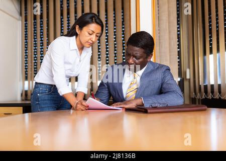 Geschäftsmann und Geschäftsfrau kommunizieren und unterzeichnen Dokumente am Verhandlungstisch im Büro Stockfoto