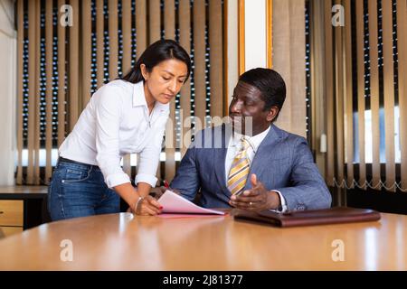 Geschäftsmann und Geschäftsfrau kommunizieren und unterzeichnen Dokumente am Verhandlungstisch im Büro Stockfoto