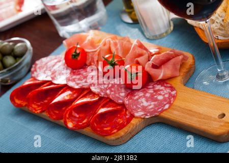 Spanische Tapas: Auf Holzbrettscheibchen werden Würstchen und Jamon serviert Stockfoto