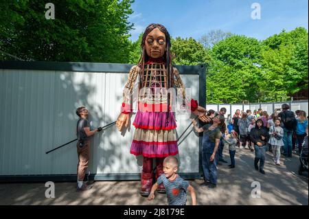 Lviv, Ukraine. 11.. Mai 2022. Menschen interagieren mit Amal, einer riesigen Marionette, die ein neunjähriges syrisches Flüchtlingsmädchen in einem Containerquartier für vertriebene Ukrainer darstellt. Die 3,5 Meter lange Riesenpuppe feiert die menschliche Migration und ist mehr als 8000 Kilometer von der syrischen türkischen Grenze durch Europa bis nach Großbritannien gereist. Russland marschierte am 24. Februar 2022 in die Ukraine ein und löste damit den größten militärischen Angriff in Europa seit dem Zweiten Weltkrieg aus Kredit: SOPA Images Limited/Alamy Live Nachrichten Stockfoto