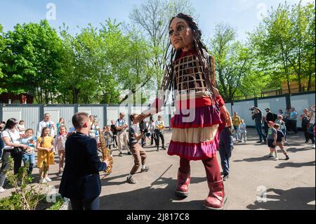 Lviv, Ukraine. 11.. Mai 2022. Menschen interagieren mit Amal, einer riesigen Marionette, die ein neunjähriges syrisches Flüchtlingsmädchen in einem Containerquartier für vertriebene Ukrainer darstellt. Die 3,5 Meter lange Riesenpuppe feiert die menschliche Migration und ist mehr als 8000 Kilometer von der syrischen türkischen Grenze durch Europa bis nach Großbritannien gereist. Russland marschierte am 24. Februar 2022 in die Ukraine ein und löste damit den größten militärischen Angriff in Europa seit dem Zweiten Weltkrieg aus (Foto von Mykola Tys/SOPA Images/Sipa USA) Quelle: SIPA USA/Alamy Live News Stockfoto